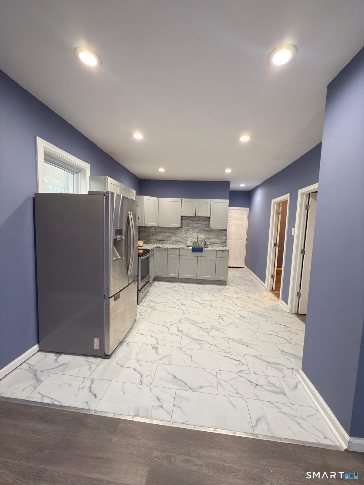 a large room with stainless steel appliances kitchen island granite countertop a refrigerator and a sink