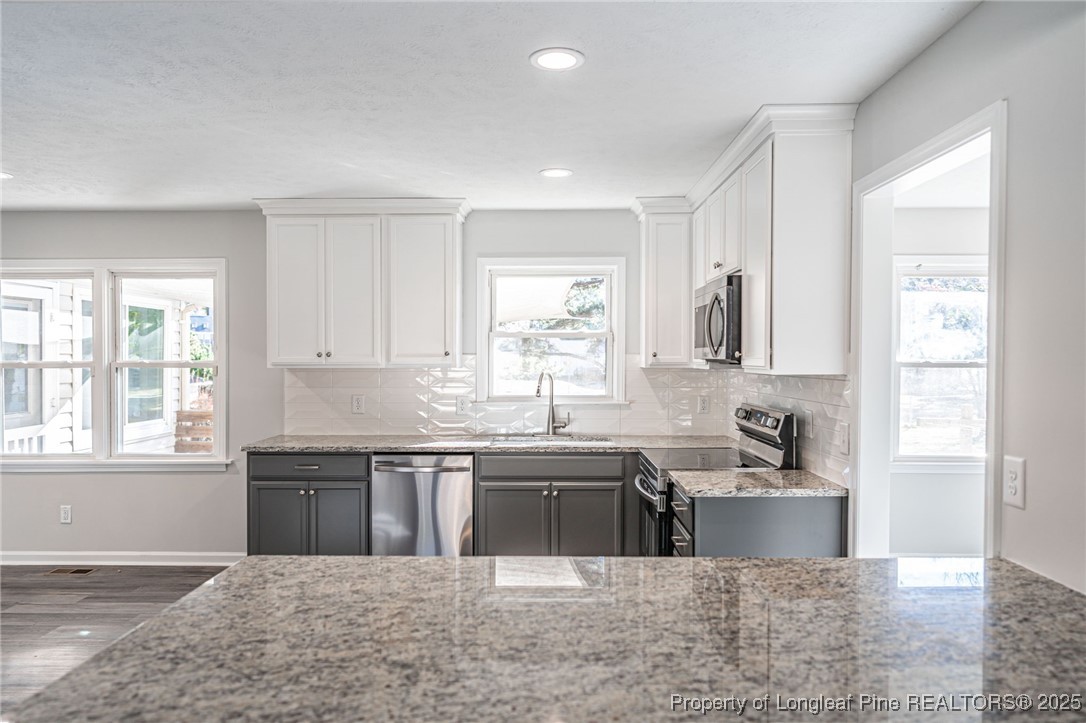 255 Foxcroft Road Whispering Pines, NC 28327 - Photo 11 of 31 a large kitchen with stainless steel appliances granite countertop a sink and a white cabinets