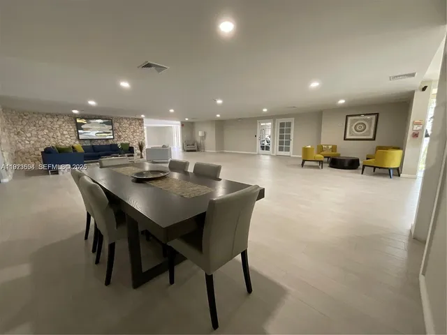 a kitchen with stainless steel appliances granite countertop a stove a sink a refrigerator a dining table and chairs