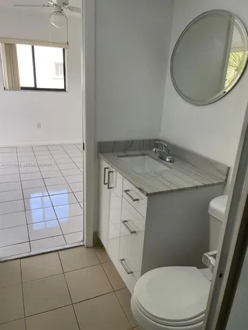 a bathroom with a granite countertop toilet sink and mirror