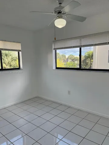 an empty room with windows and fan