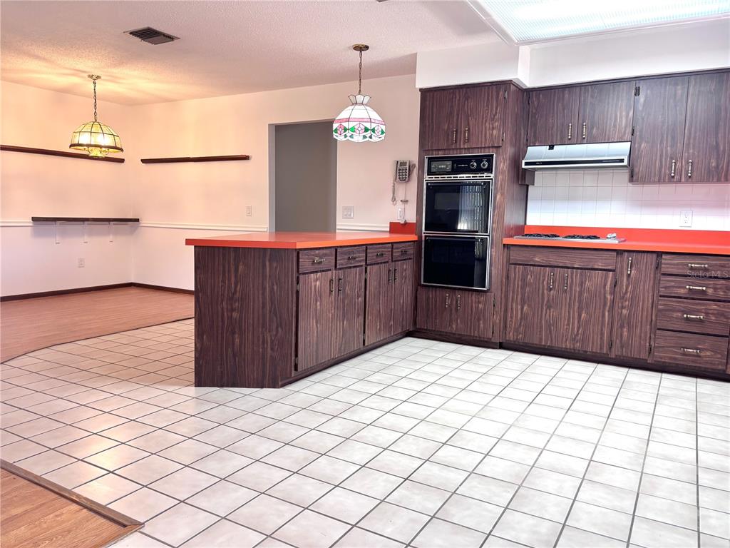 324 Alemander Avenue DeBary, FL 32713 - Photo 8 of 40 a kitchen with a wooden floor and a refrigerator
