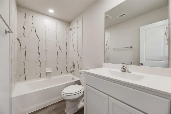 a bathroom with a toilet a sink a mirror a bathtub and vanity