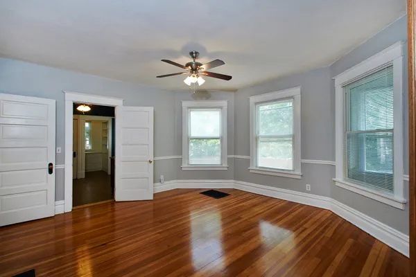 a view of empty room with wooden floor and fan