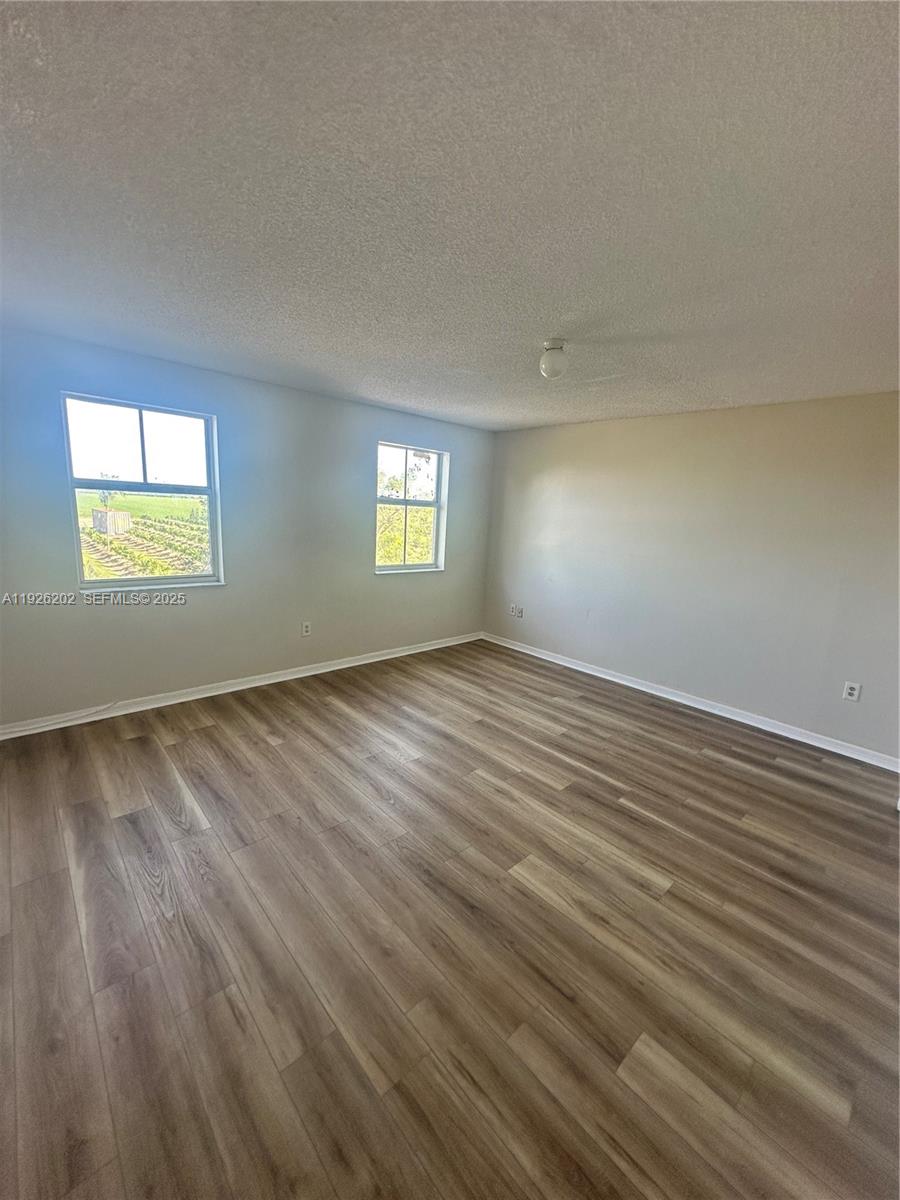 27347 Southwest 117th Place Homestead, FL 33032 - Photo 19 of 37 a view of an empty room with wooden floor and a window