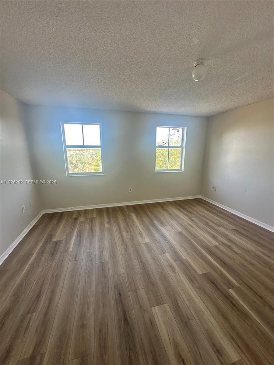 27347 Southwest 117th Place Homestead, FL 33032 - Photo 21 of 37 an empty room with wooden floor and windows