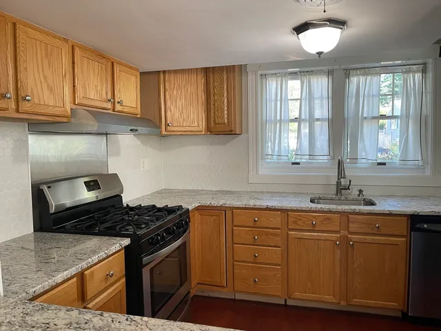 a kitchen with granite countertop stainless steel appliances a stove sink and cabinets
