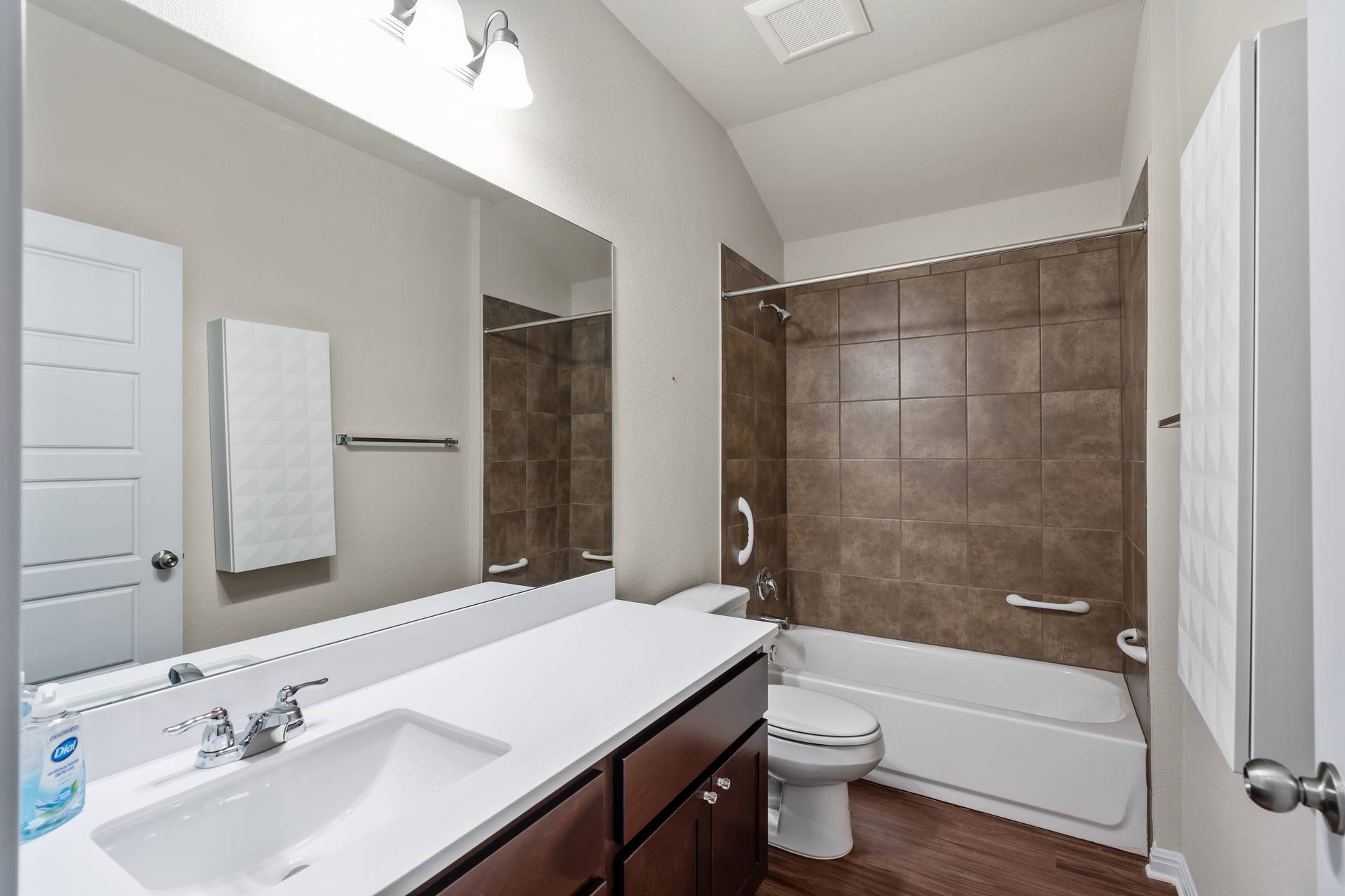 16512 Enamorado Road Manor, TX 78653 - Photo 2 of 31 A well-appointed bathroom features a single vanity, bath and shower combination, and rich wood-look flooring.