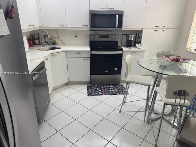 a kitchen with white cabinets and sink