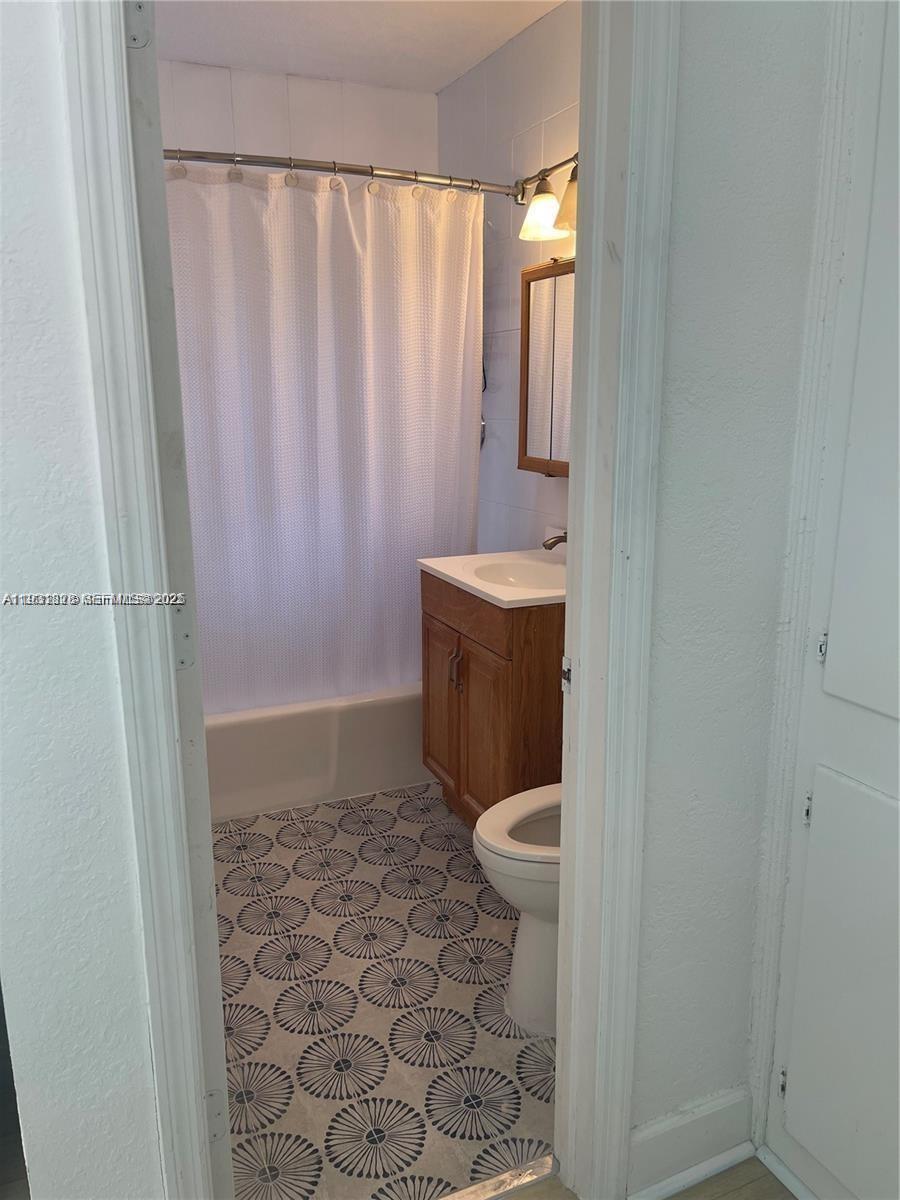 1560 Northeast 145th Street, Unit 1 Miami, FL 33161 - Photo 7 of 11 a bathroom with a toilet and a shower curtain