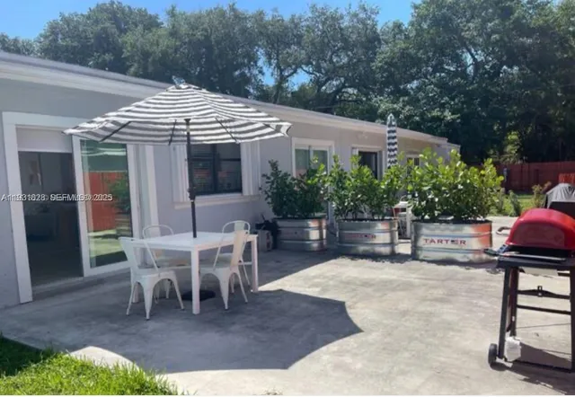 a patio with a table and chairs and potted plants