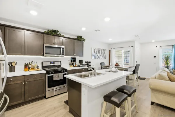 a kitchen with a sink a stove a refrigerator cabinets and chairs