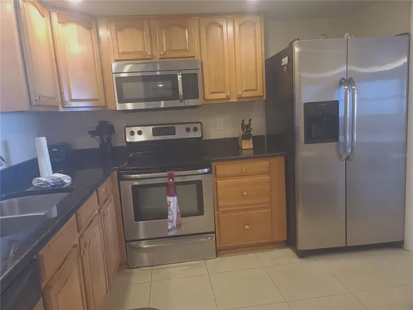 a kitchen with granite countertop a stove and a microwave with cabinets
