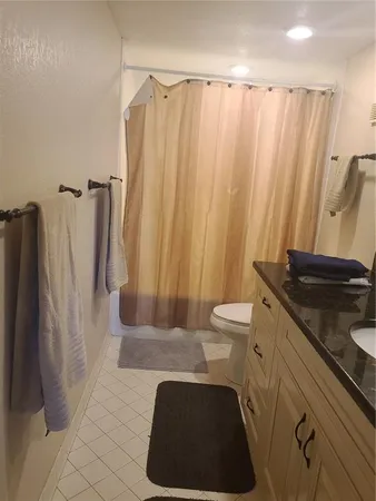 a bathroom with a granite countertop toilet sink and mirror