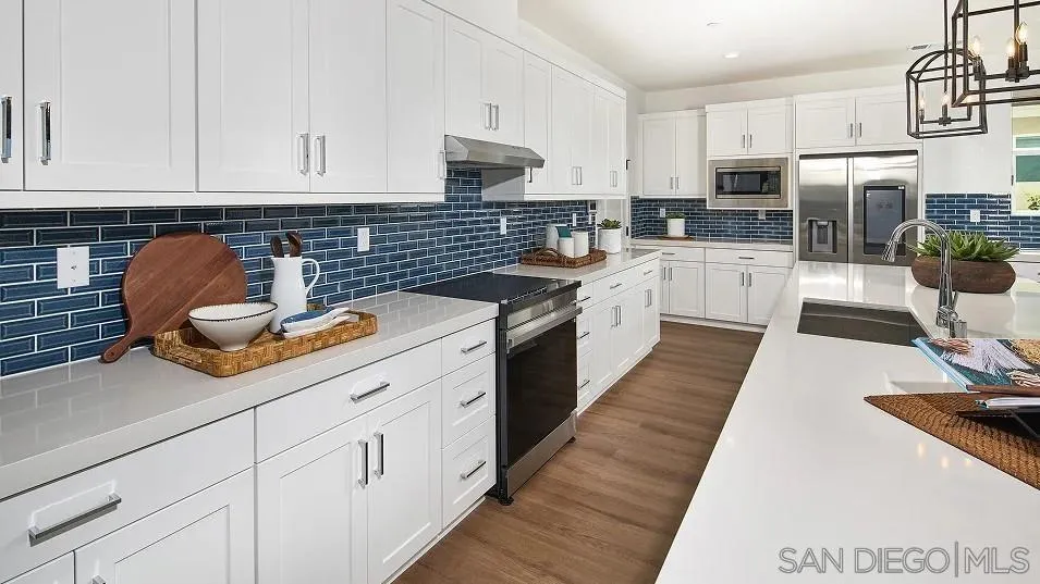 130 Mellano Way Oceanside, CA 92057 - Photo 3 of 26 a kitchen with kitchen island granite countertop a sink dishwasher stove and white cabinets with wooden floor