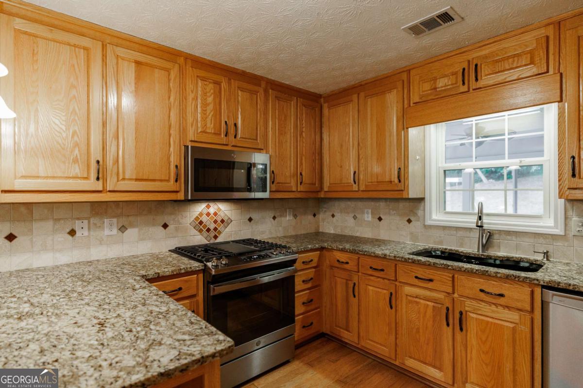 2249 Cluster Lane Grayson, GA 30017 - Photo 15 of 53 a kitchen with granite countertop wooden cabinets and a stove top oven
