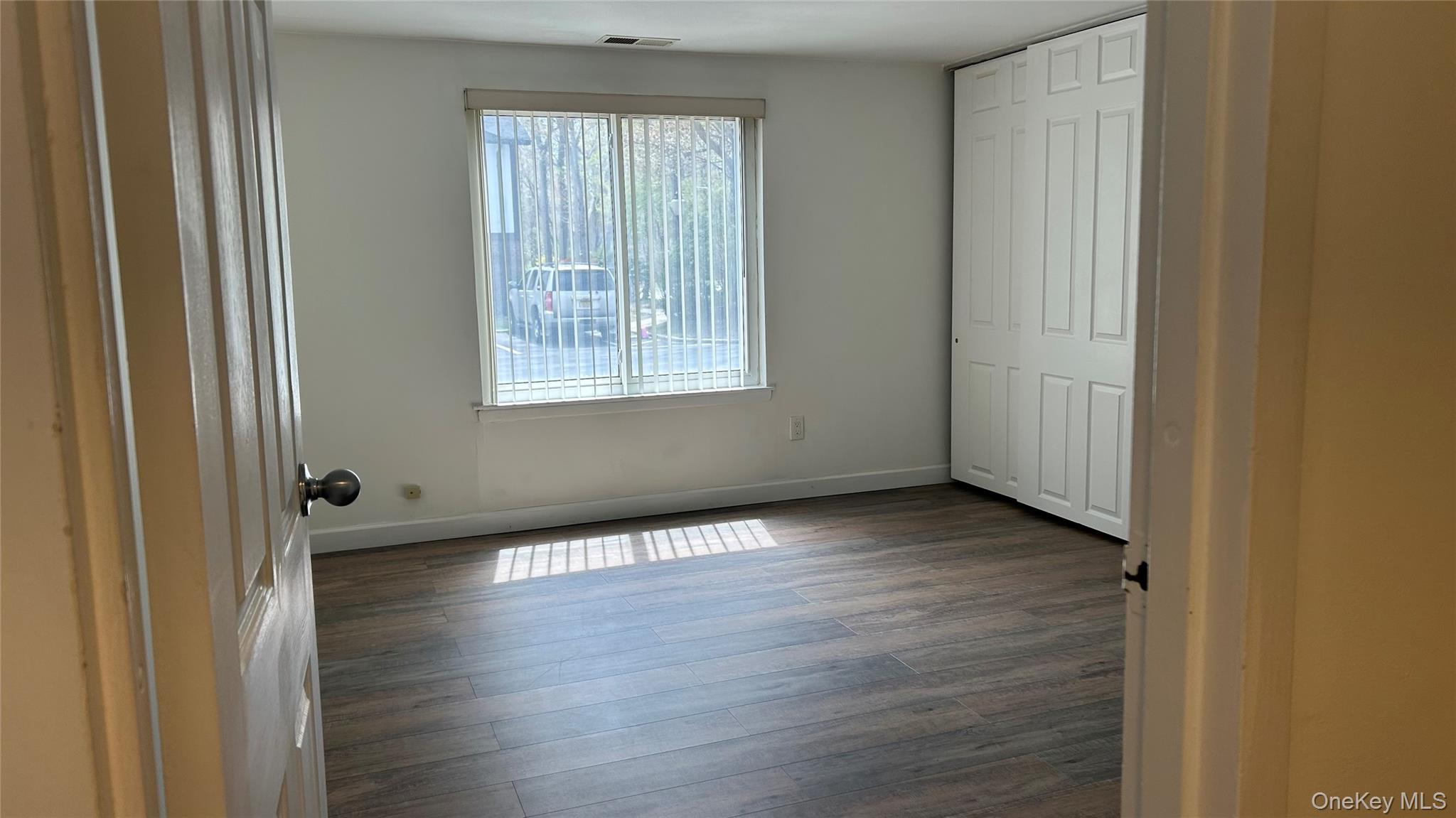 103 Birchwood Road, Unit 103 Medford, NY 11763 - Photo 9 of 13 a view of an empty room with wooden floor and a window