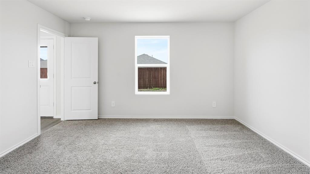 3319 Twilight Trail Forney, TX 75126 - Photo 18 of 33 Light gray carpeted room with a white window frame, white baseboards, and a white two-panel interior door