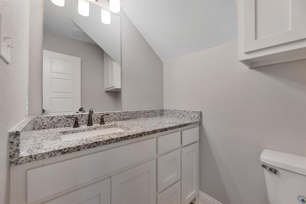 1713 Bronco Road Granbury, TX 76049 - Photo 5 of 23 Bathroom vanity featuring a white shaker-style cabinet, speckled countertop, an undermount sink, and dark bronze-finish fixtures