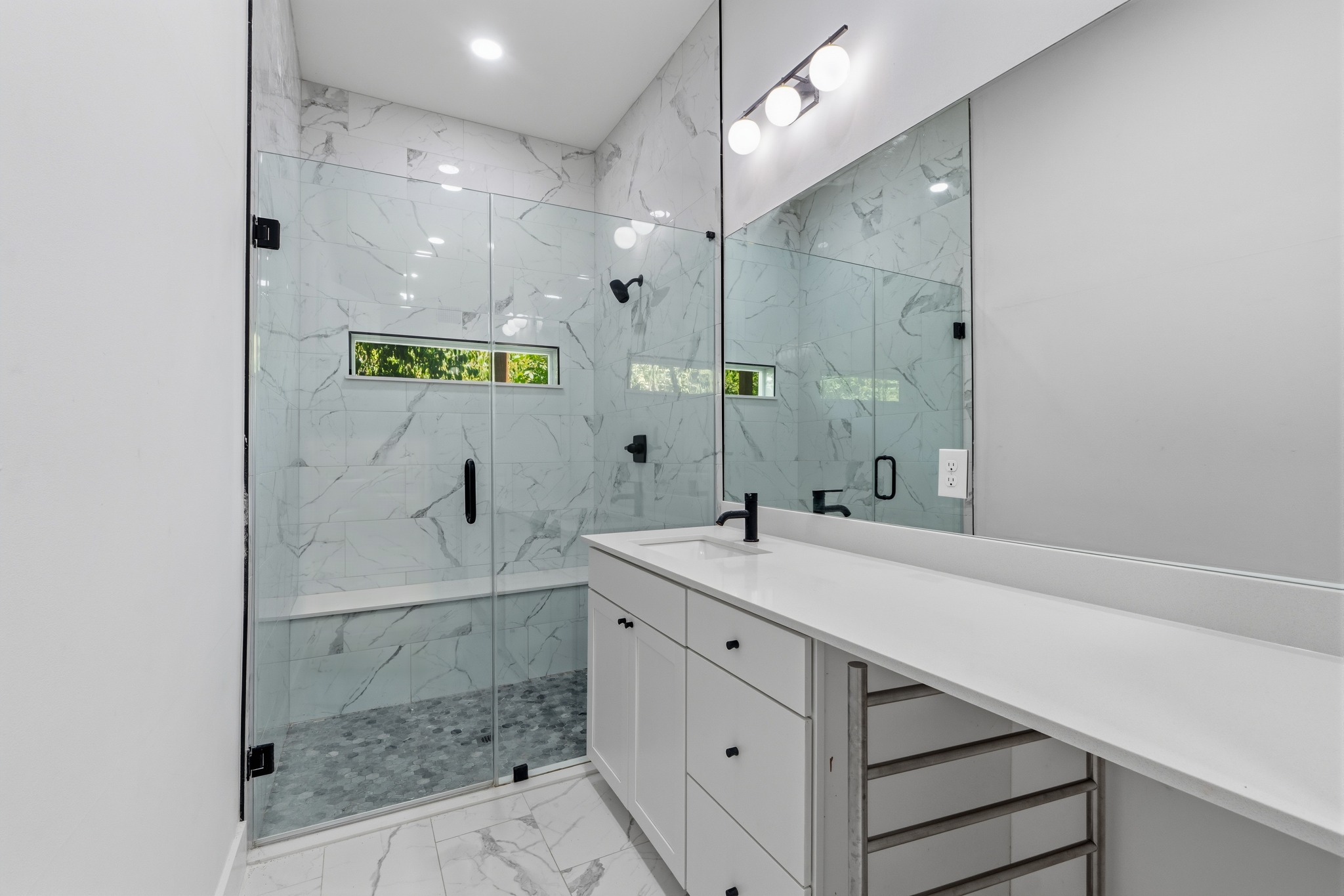 5010 Baker Street Austin, TX 78721 - Photo 15 of 22 Floor-to-ceiling marble tile accents the glass-enclosed walk-in shower and matching tiled floor.