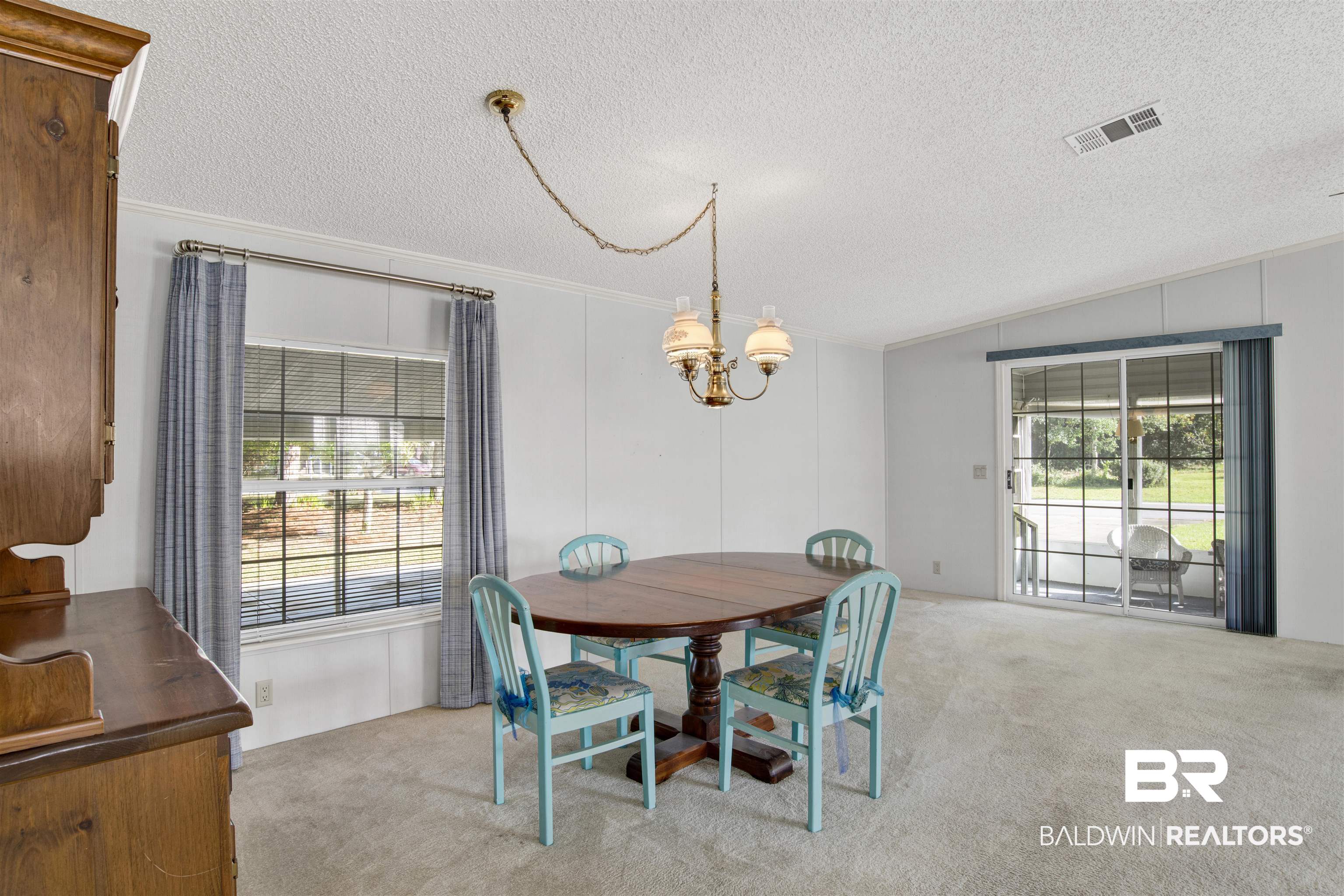 1216 Ridgewood Drive Lillian, AL 36549 - Photo 7 of 29 Dining area featuring light carpet, a textured ceiling, a decorative wall, vaulted ceiling, and a chandelier