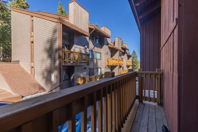 a view of balcony with two plants and wooden fence