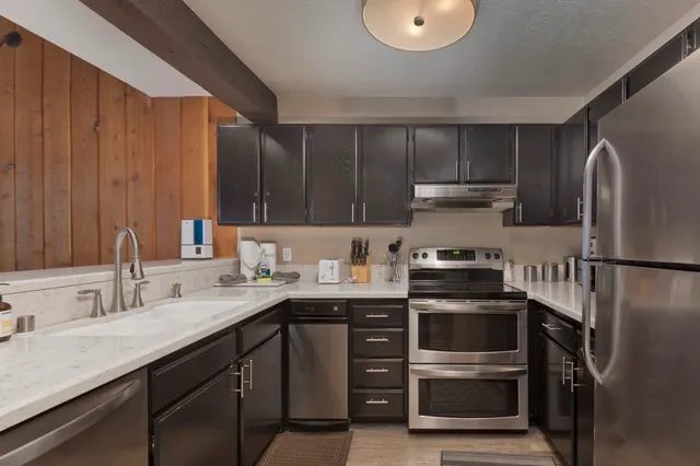 a kitchen with stainless steel appliances a sink a stove and cabinets