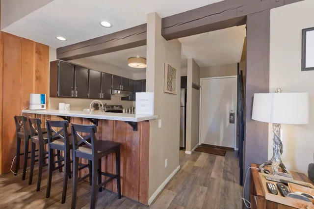a kitchen with kitchen island granite countertop wooden floors and refrigerator