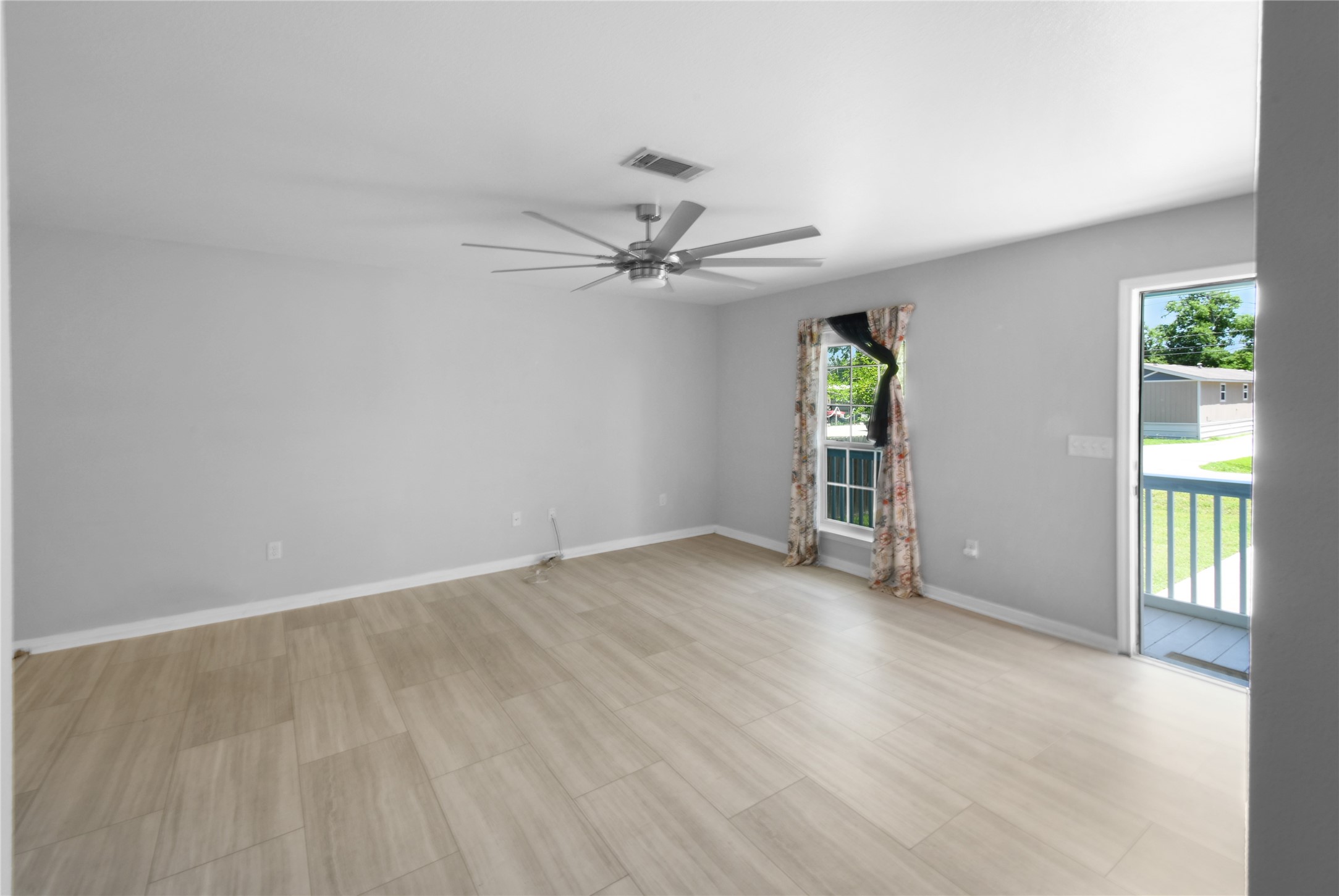 320 10th Street Dickinson, TX 77539 - Photo 13 of 21 This bright and spacious living area features modern flooring, a sleek ceiling fan, and abundant natural light from large windows, seamlessly connecting to the outdoors for a welcoming and airy ambiance.