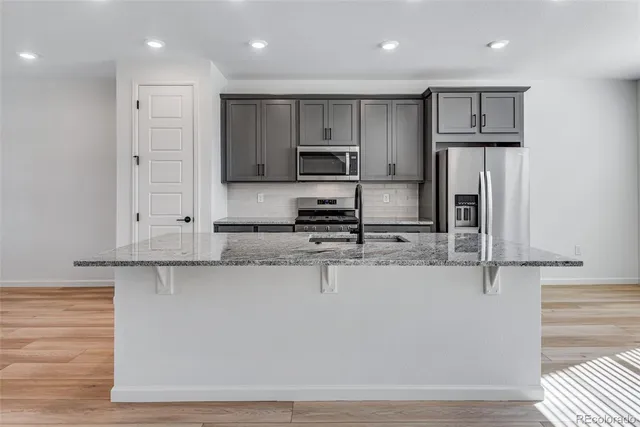 a large kitchen with stainless steel appliances granite countertop a stove a sink and a microwave