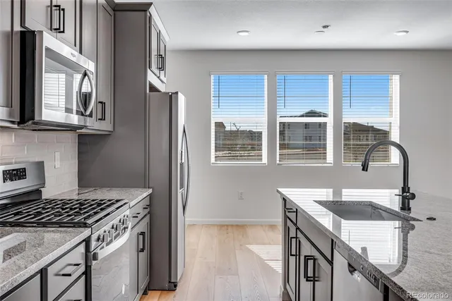 a kitchen with stainless steel appliances granite countertop a stove a sink and a refrigerator