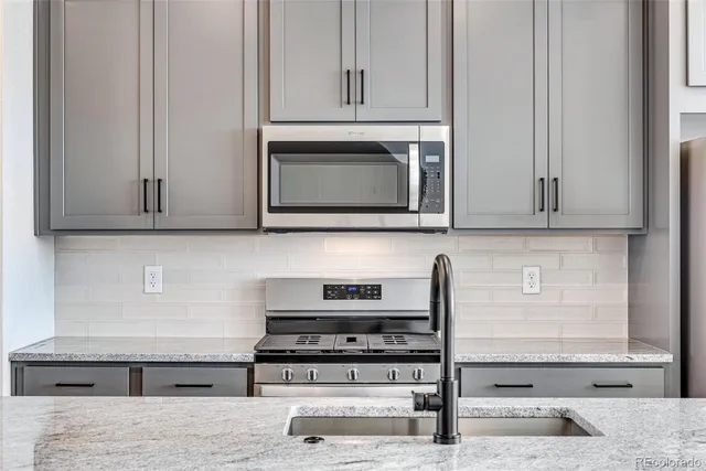 a kitchen with stainless steel appliances granite countertop white cabinets and a stove top oven