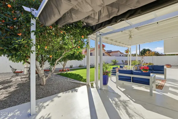 a view of a white house in front of a big yard with potted plants