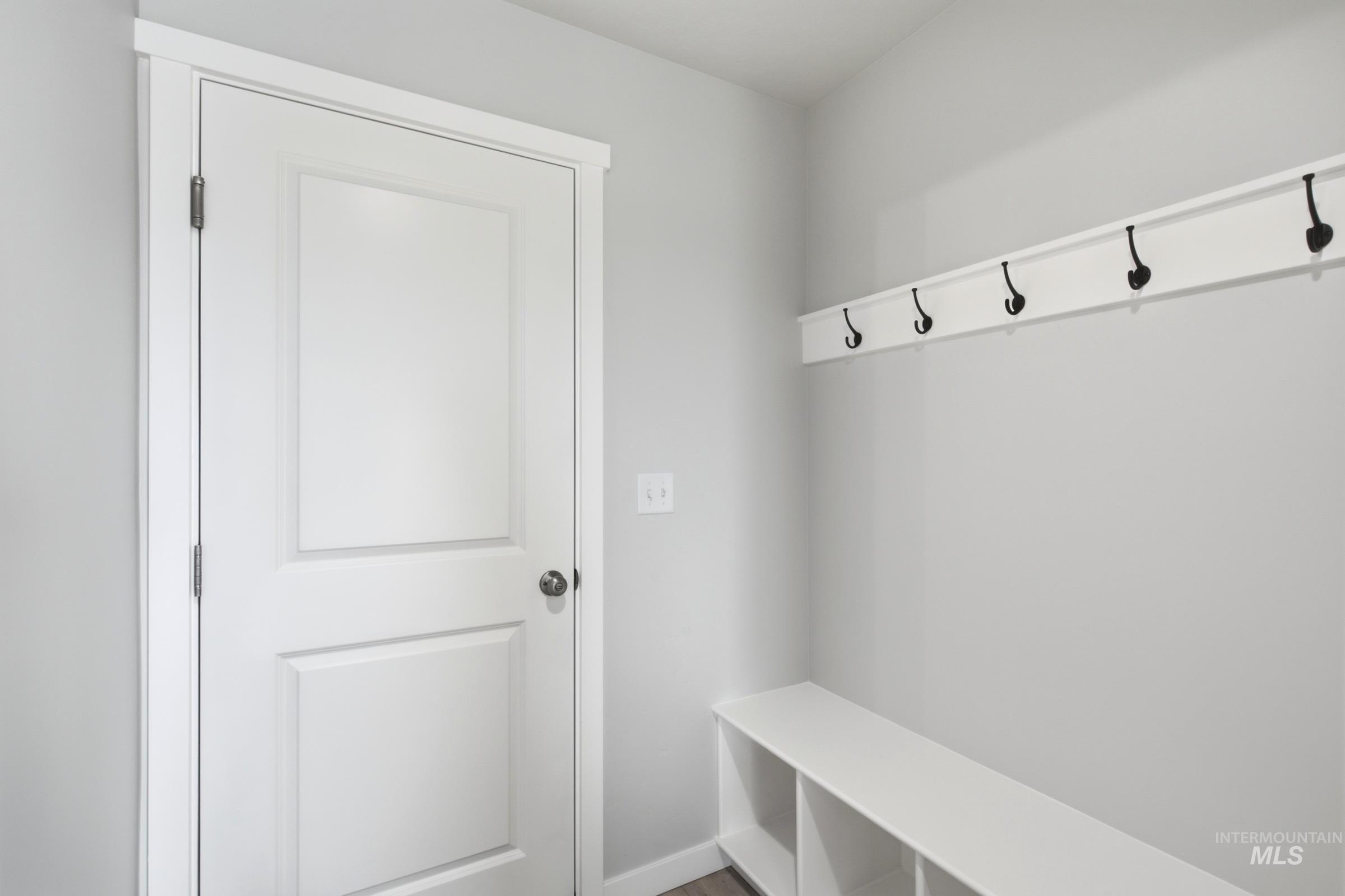 13324 Bank Street Caldwell, ID 83607 - Photo 11 of 29 Built-in storage bench with cubbies, white panel door, and wall-mounted coat rack