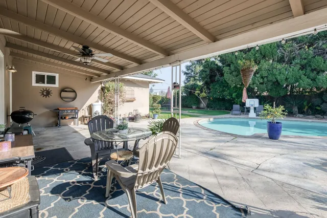 a view of a patio with table and chairs potted plants and large tree