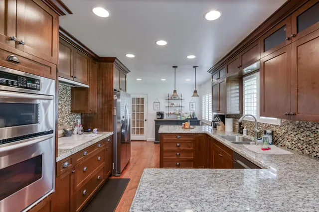 a kitchen with stainless steel appliances granite countertop a sink window and cabinets