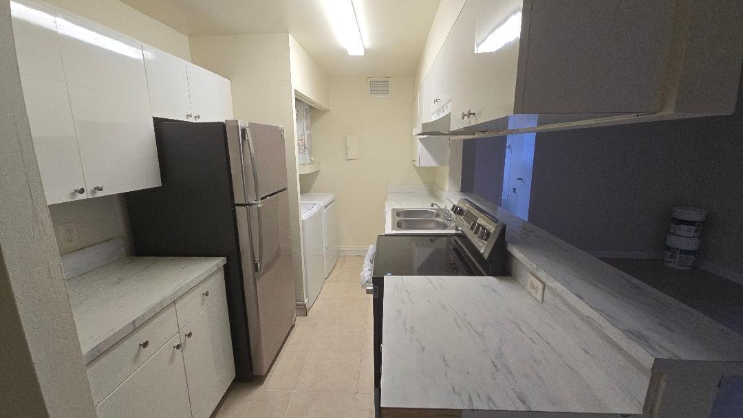4403 Treehouse Lane, Unit H Tamarac, FL 33319 - Photo 2 of 26 a kitchen with a refrigerator and a sink