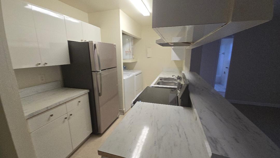 4403 Treehouse Lane, Unit H Tamarac, FL 33319 - Photo 3 of 26 a kitchen with a refrigerator and cabinets