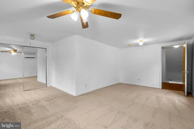 an empty room with a chandelier fan and windows