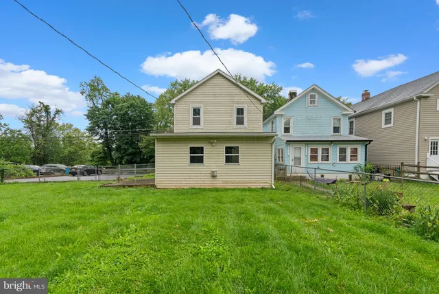 a view of a house with a big yard potted plants and large tree