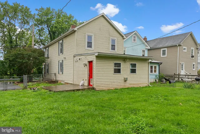 a view of a house with a yard and lawn chairs with wooden fence