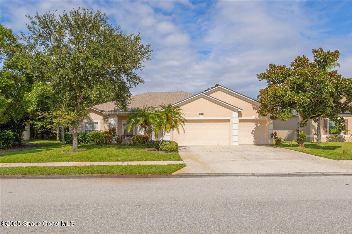 a view of a house with a yard and large trees