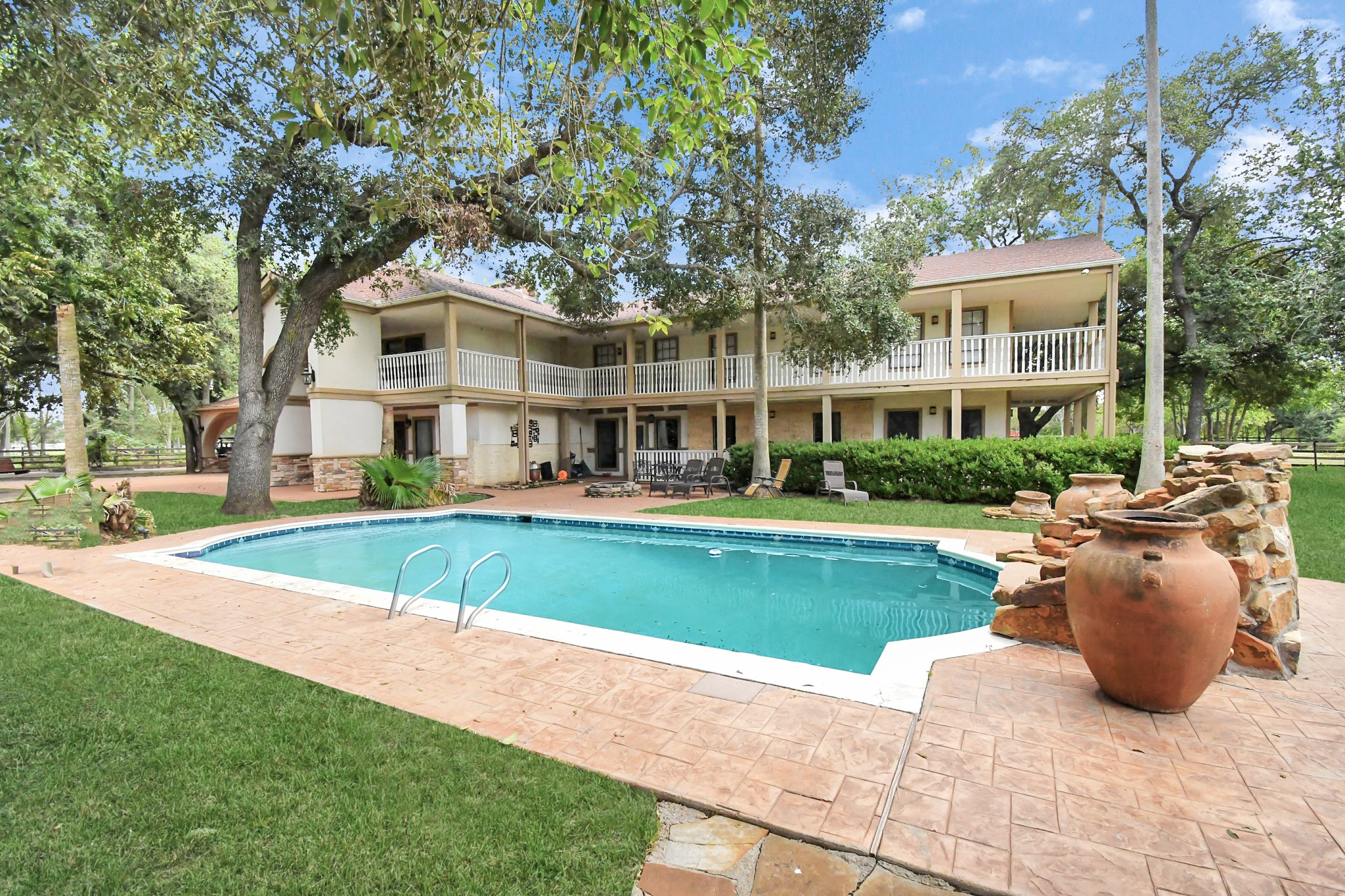 1347 Seidel Road Brookshire, TX 77423 - Photo 3 of 50 This spacious estate boasts a resort-style pool, rustic water feature, and expansive balconies, all surrounded by mature trees and peaceful greenery.