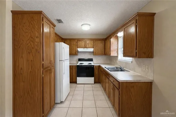 a kitchen with a refrigerator a sink and wooden cabinets