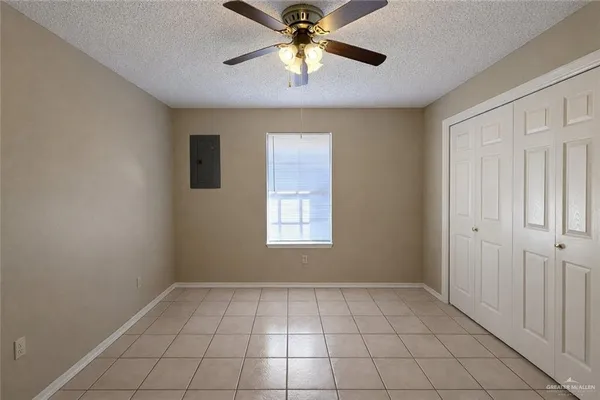a view of an empty room with window and chandelier fan