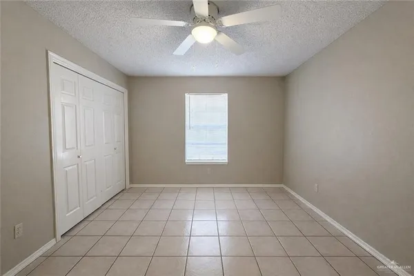 a view of an empty room with window and chandelier fan