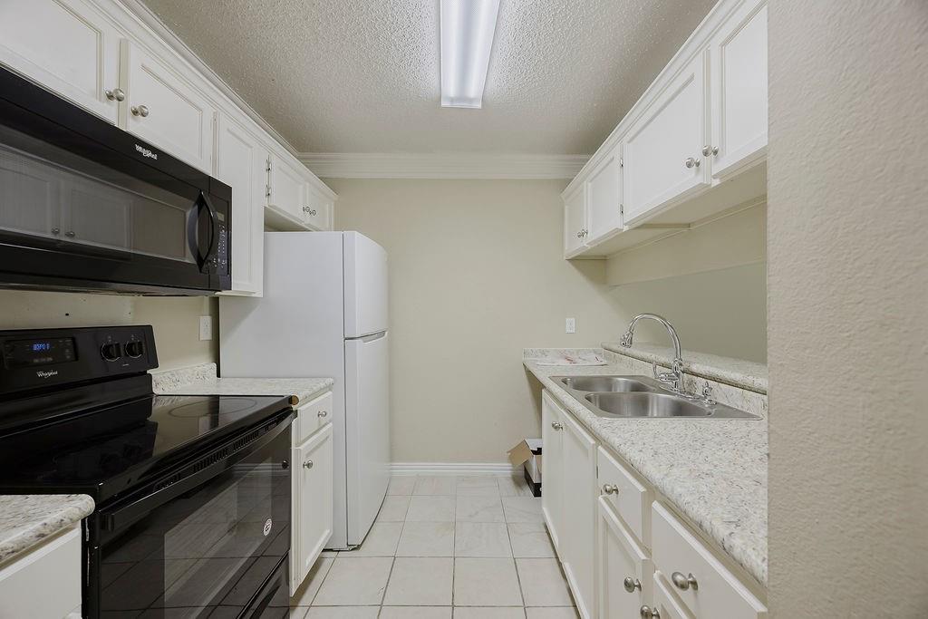 2200 East Trinity Mills Road, Unit 214 Carrollton, TX 75006 - Photo 8 of 25 a kitchen with a sink stove and microwave