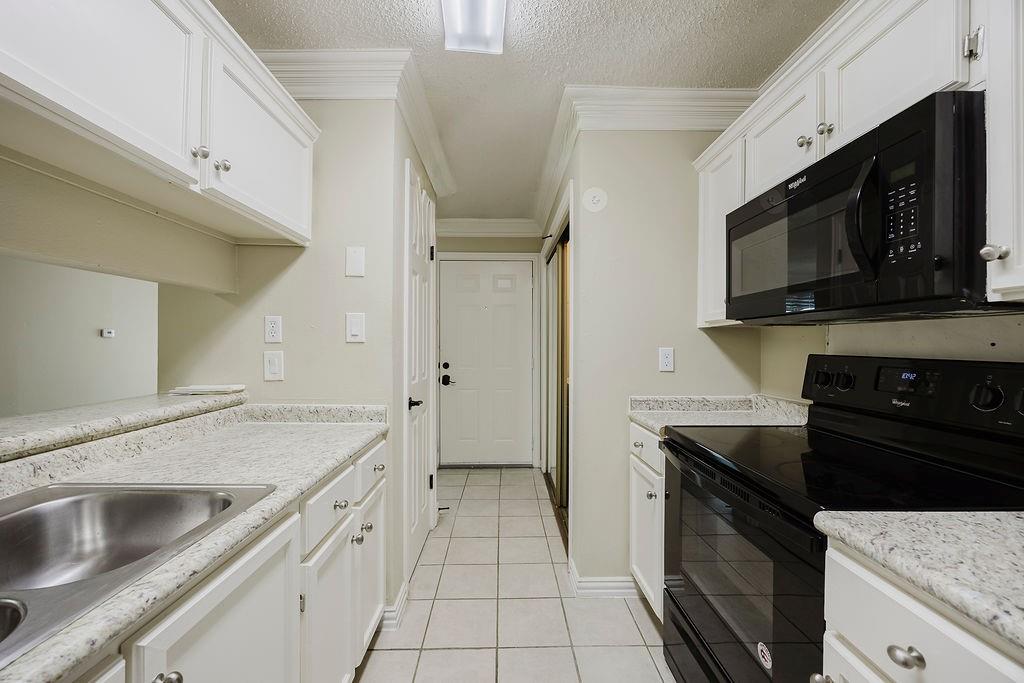 2200 East Trinity Mills Road, Unit 214 Carrollton, TX 75006 - Photo 9 of 25 a kitchen with a sink stove and microwave
