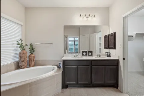 a bathroom with a tub sink and mirror