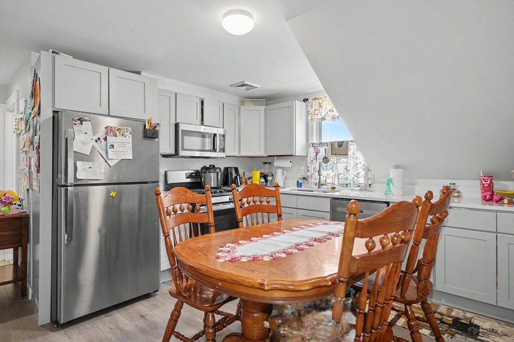 5 Eddy Street, Unit 2 Webster, MA 01570 - Photo 10 of 18 a kitchen with stainless steel appliances a refrigerator a stove a dining table and chairs